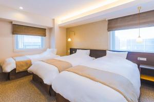 京都市にあるホテル エムズ・エスト四条烏丸のベッド3台と窓が備わるホテルルームです。