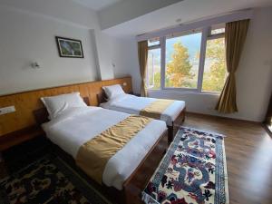 two beds in a room with a window and a rug at Martam Village Homestay in Gangtok
