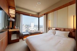 ein Hotelzimmer mit einem Bett und einem großen Fenster in der Unterkunft Candeo Hotels Nankai Wakayama in Wakayama