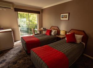 a hotel room with two beds and a balcony at Quality Hotel Bayswater in Perth