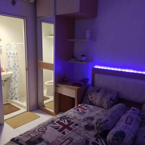 a purple bedroom with a bed and a bathroom at Bintang Property Aeropolis in Rawabambu