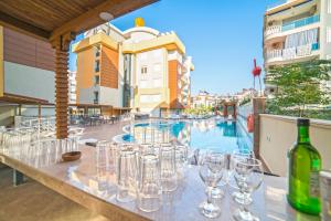 a table with wine glasses on a balcony with a pool at Flamingo Residence in Antalya