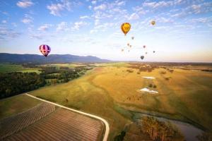 un grupo de globos de aire caliente volando sobre un campo en Cessnock Vintage Motor Inn en Cessnock