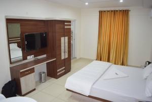 a bedroom with a large bed and a tv in it at hotel fortune suites in Bangalore