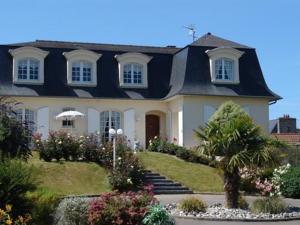 een groot wit huis met een zwart dak bij Chambres d'hôtes La Mansardière in Cancale