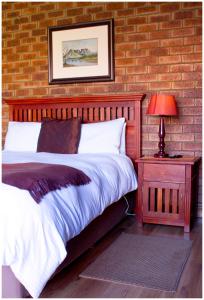 ein Schlafzimmer mit einem Bett und einem Tisch mit einer Lampe in der Unterkunft Asante Guest House in Vanderbijlpark