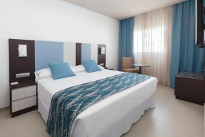 a bedroom with a large white bed with blue sheets at Hotel Riu Costa del Sol - All Inclusive in Torremolinos