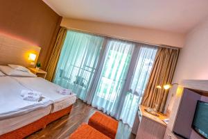 "ハルカーニャ"にあるTermál Kemping Apartmanok és Bungalókのベッドと大きな窓が備わるホテルルームです。