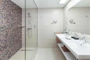 
a bathroom with a sink, mirror, and shower stall at Hotel Riu Costa del Sol - All Inclusive in Torremolinos
