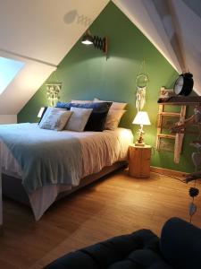- une chambre avec un lit et un mur vert dans l'établissement Le sauna de l'homme de Bois by Naturogite, à Honfleur
