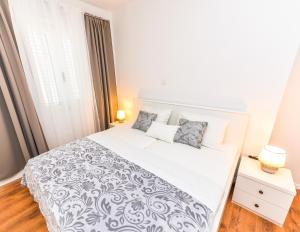 a bedroom with a large white bed and a window at Apartments Ankica in Novalja