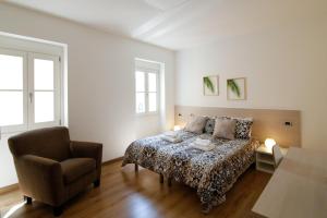 una camera con un letto e una sedia di Conte Durini Apartments & Rooms ad Arcore