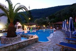 a hotel with a pool with chairs and a palm tree at Afroditi in Panormos Skopelos