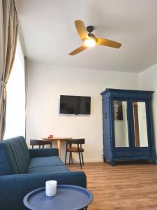 un soggiorno con divano blu e ventilatore a soffitto di Blue Seagull Taikos 13-28 a Nida