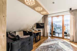 a living room with a table and chairs and a desk at Aparthotel Prestige in Zakopane