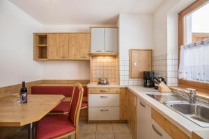 cocina con mesa de madera, fregadero y encimera en Wollbach - Gruberhof, en San Giacomo