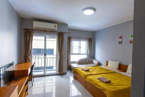 a bedroom with a yellow bed and a balcony at Fenix in Pathum Thani