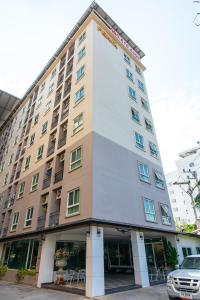 a hotel building with a car parked in front of it at Fenix in Pathum Thani