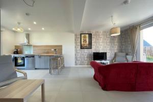 sala de estar con sofá rojo y cocina en Belle maison neuve à 10 minutes de Chambray-lès-Tours, en Esvres