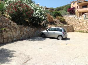 un pequeño coche estacionado junto a una pared de piedra en Residence Mare Sol Appartamento in affitto Budoni, en Porto Ottiolu