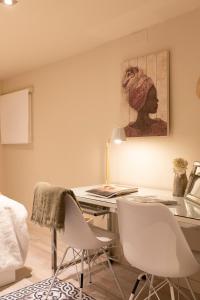 バルセロナにあるChic Apartments Barcelonaのデスク、椅子2脚、絵画が備わる客室です。