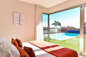 a bedroom with a bed and a view of a swimming pool at Sunshine by VillaGranCanaria in Maspalomas