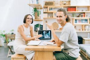 a man and woman sitting at a table with a laptop at Cantagua Hostel in Valencia