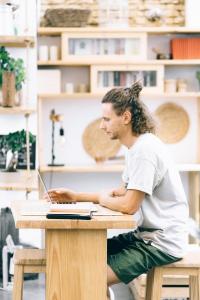 un hombre sentado en un escritorio con un ordenador portátil en Cantagua Hostel en Valencia