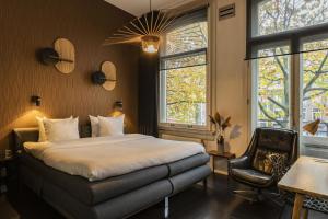 a bedroom with a bed and a chair and windows at Hotel V Frederiksplein in Amsterdam