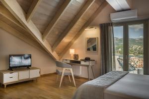 een slaapkamer met een bed, een bureau en een televisie bij Grand View Maisonette in Argostoli