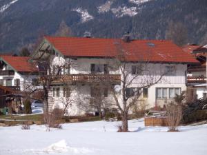 un grand bâtiment avec un toit rouge dans la neige dans l'établissement Haus Schmauß - Chiemgau Karte, à Inzell