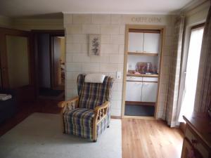 a living room with a chair and a kitchen at Haus Schmauß - Chiemgau Karte in Inzell