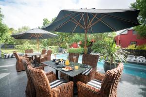 un patio con tavoli, sedie e ombrellone di Ruby Rose a Riebeek-Wes