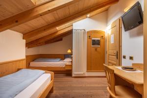 a bedroom with two beds and a desk and a tv at Agriturismo Maso Santa Libera in Tesero