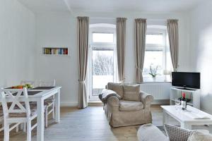 a living room with a couch and a chair and a table at App-6-mit-Suedbalkon-in-strandnaher-Lage-Baederstil-Villa-in-Wenningstedt-Sylt in Wenningstedt