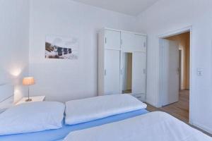 a white bedroom with two beds and a lamp at App-6-mit-Suedbalkon-in-strandnaher-Lage-Baederstil-Villa-in-Wenningstedt-Sylt in Wenningstedt
