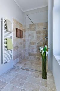 a bathroom with a shower with a vase of flowers at App-6-mit-Suedbalkon-in-strandnaher-Lage-Baederstil-Villa-in-Wenningstedt-Sylt in Wenningstedt