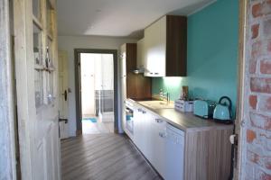 a kitchen with white cabinets and a blue wall at Kleine Schwalbe in Kabelhorst