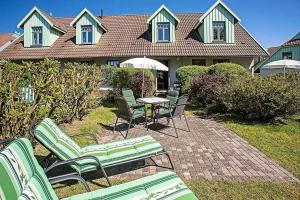 eine Terrasse mit Stühlen, einem Tisch und einem Sonnenschirm in der Unterkunft Ferienhaussiedlung Strandperlen Küstenhof 2c Typ V in Wustrow