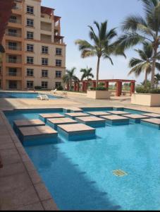 een groot zwembad met palmbomen en een gebouw bij مسكن الشاطئ Beach House in King Abdullah Economic City