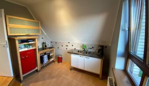 cocina con fregadero y nevera roja en *To hus* Wohnung am Rande von Jever, en Jever