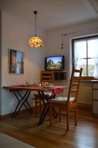 une salle à manger avec une table, des chaises et une télévision dans l'établissement Ferienwohnung Chiemseestrand Nr. 16, à Arlaching