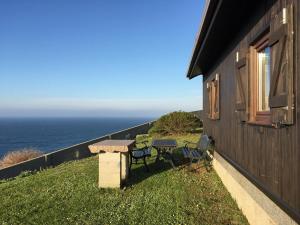 a table and chairs on the side of a house with the ocean at Bungalow 1 - Playa Arnela in Carballo
