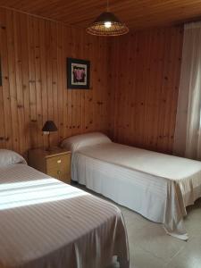 two beds in a room with wooden walls at Bungalow 1 - Playa Arnela in Carballo +28 photos