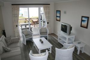 a living room with a couch and chairs and a tv at La Best Pinnacle Point Lodges & Villa in Mossel Bay