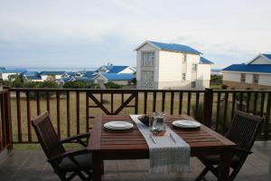 una mesa de madera con 2 sillas en el balcón en La Best Pinnacle Point Lodges & Villa, en Mossel Bay
