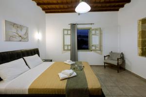 a bedroom with a bed and a chair and a window at Basilikos traditional house, 10' from Falasarna in Kissamos