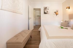 Habitación blanca con cama y banco. en beachome4u2, en Carcavelos
