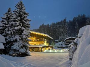 um edifício coberto de neve com uma árvore em primeiro plano em Gasthof Schlossberghof em Lienz