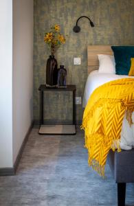 1 dormitorio con cama y mesa con manta amarilla en Hotel - Restaurant Les 3 Piliers, en Le Boupère